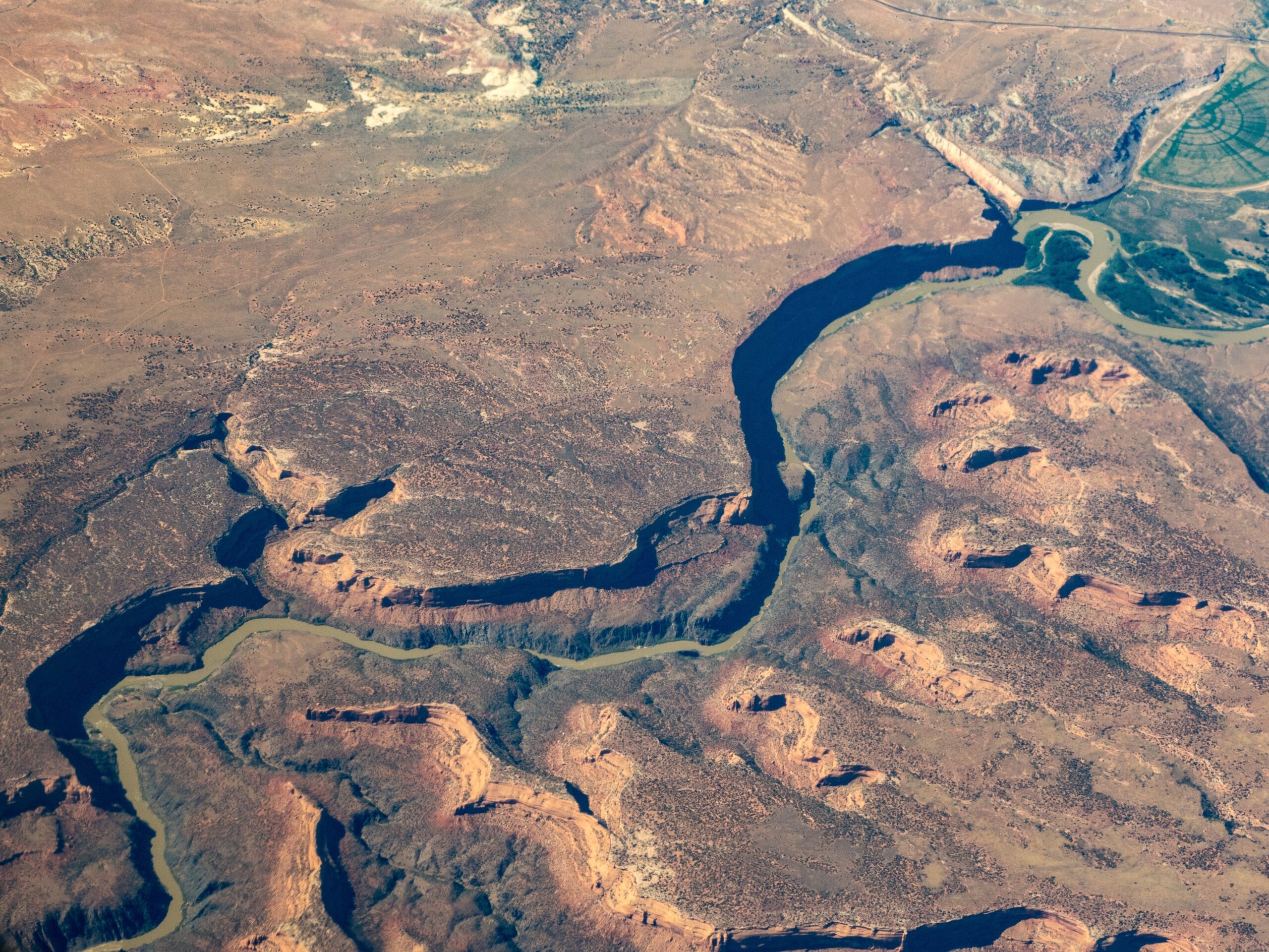 Aerial view of the Colorado river snaking across the desert with gorges and cliffs